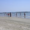 Persone in spiaggia con acqua bassa e cielo azzurro.
