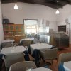 Interno di ristorante con tavoli apparecchiati e un banco da cucina.