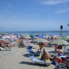 Spiaggia vivace con ombrelloni colorati, persone rilassate e il mare sullo sfondo.