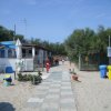 Una passerella su una spiaggia con cabine e bidoni colorati.