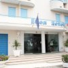 Facciata di un hotel con ingresso a vetri, scalini e bandiere europee.