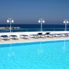 Piscina all'aperto con lettini, lampioni e vista sul mare.