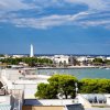 Vista panoramica di una città costiera con un faro e un mare limpido.