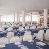 Sala da pranzo con tavoli apparecchiati e sedie bianche.
