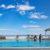 Piscina all'aperto con persone, cielo blu e nuvole bianche, cerchi di luce.