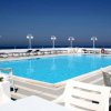 Piscina all'aperto con lettini e vista sul mare.