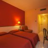 Camera d'hotel con due letti singoli e pareti rosse.
