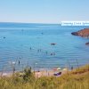 Spiaggia affollata con ombrelloni colorati e persone che nuotano nel mare.