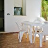 Tavolo e sedie bianche su terrazza pavimentata.