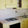 Cucina con mobili gialli, piano cottura e lavello in acciaio.