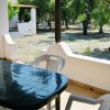 Tavolo nero e sedie su una veranda con vista su un giardino alberato.