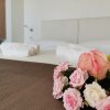 Letto con lenzuola bianche, fiori rosa e asciugamani piegati.