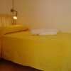 Letto singolo con copriletto giallo, lampada da lettura e asciugamani bianchi piegati.
