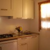 Una cucina bianca con fornelli, lavandino e fiori sul piano di lavoro.