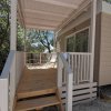 Una veranda in legno con sedie bianche, circondata da alberi.