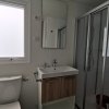 Bagno compatto con doccia, WC, lavandino con mobile in legno e specchio.