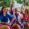 Tre donne in costumi colorati che ballano su un palco di legno.