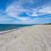 Spiaggia di ciottoli sotto un cielo blu.