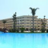Ampia piscina davanti a un hotel con palme.