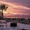 Tramonto sulla spiaggia con palme e ombrelloni.