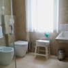 Bagno con lavabo, doccia, vaso e finestra con tenda.