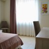 Camera con letto matrimoniale, tendaggi chiari e scrivania.