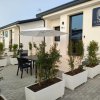 Esterno di un edificio moderno con piante, tavoli e ombrelloni.