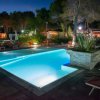 Piscina notturna con lettini e ombrelloni.