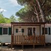 Una casa mobile con terrazza in legno, circondata da alberi alti.