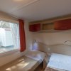 Interno di una casa mobile con due letti singoli, finestra e armadietti rossi.