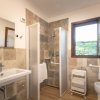 Un bagno moderno con doccia aperta, lavabo e finestra aperta.