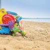 Una rete contenente giochi colorati sulla sabbia con il mare sullo sfondo.