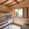 Cameretta con letto a castello, finestra aperta e divano blu a quadri.
