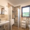 Bagno con lavabo, doccia, bidet e finestra; pareti in piastrelle decorate.