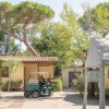 Persona su golf cart davanti a edifici gialli con giardino e pini alti.
