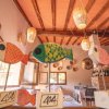 Tre pesci decorativi colorati su supporti, appesi in un ristorante con soffitto in legno e lanterne.