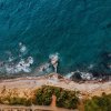 Vista aerea di una spiaggia rocciosa con onde che si infrangono.