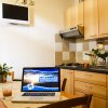 Cucina in legno chiaro con tavolo, laptop aperto e succo d'arancia, TV a muro.