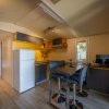 Cucina moderna con tavolo alto, sedie, frigorifero e zona notte sullo sfondo.