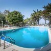 Piscina all'aperto circondata da alberi e lettini.