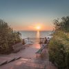 Un tramonto visto da un terrazzo con panchine e vegetazione.