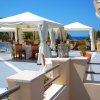 Tavoli e sedie sotto gazebo bianchi su una terrazza vista mare, con cielo blu.