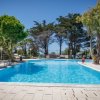 Una piscina all'aperto circondata da alberi e lettini.