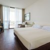Stanza d'hotel con letto matrimoniale e poltrona vicino a una finestra.