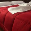 Letto con copriletto rosso e asciugamani bianchi piegati.