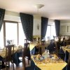 Sala da pranzo con tavoli apparecchiati e tovaglie gialle.