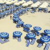 Spiaggia con ombrelloni e sedie a sdraio blu.