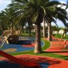Parco giochi con palme e scivoli colorati.