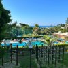 Area giochi con piscina, alberi e vista mare in lontananza.