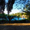 Piscina circondata da alberi e lettini sotto ombrelloni, con vista sul mare.